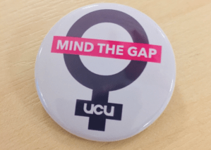 Image of UCU campaign button with a symbol of a woman with a banner across saying "mind the gap"